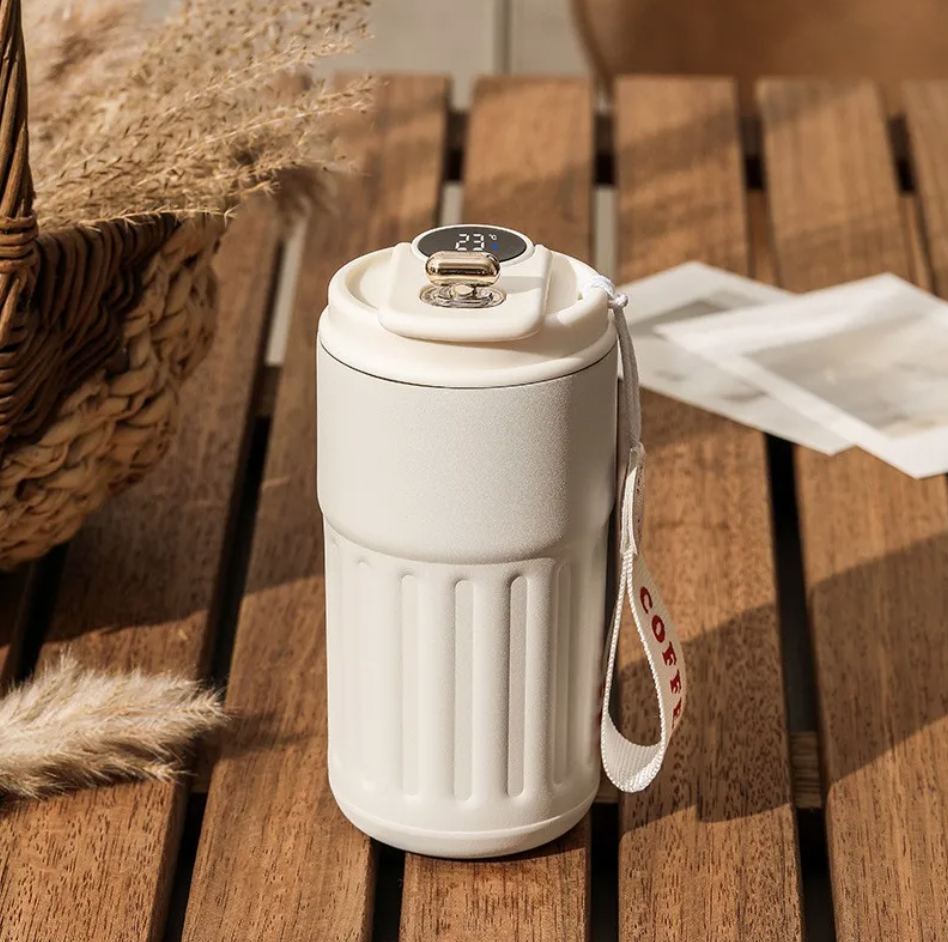 Embera smart thermal bottle in warm sand color with LED temperature display on the lid, resting on a wooden outdoor table